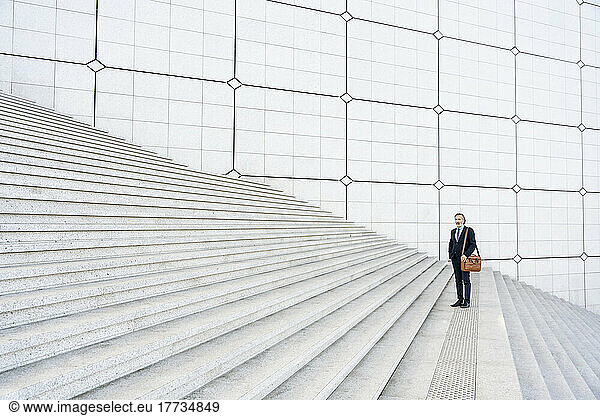Mature businessman with bag standing on steps