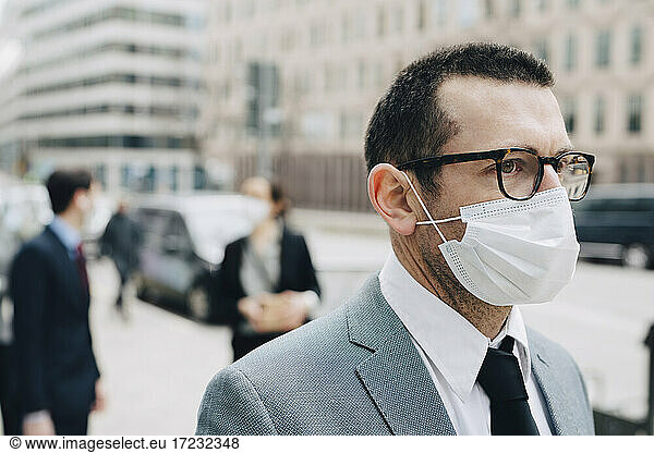 Mature businessman with protective face mask in city