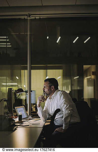 Mature businessman working on computer in work place at night