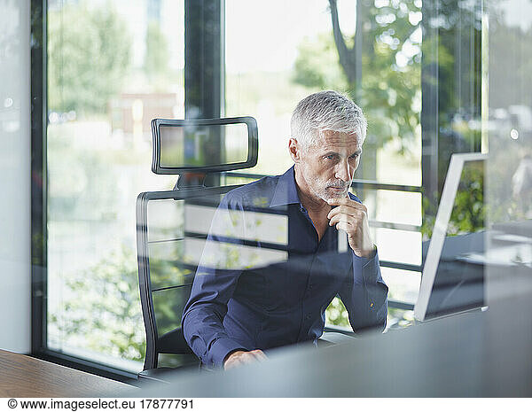 Mature businessman working on desktop PC in office