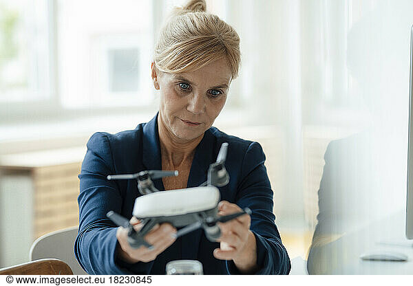 Mature businesswoman analyzing drone at office