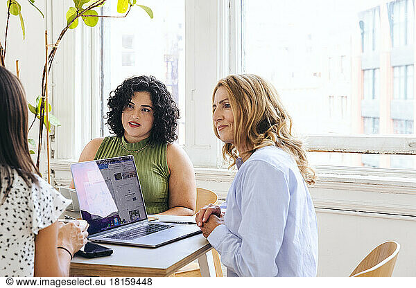 Mature businesswoman discussing ideas with female colleagues