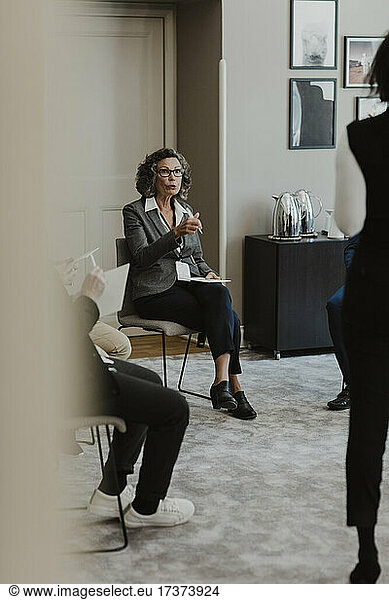 Mature businesswoman discussing with male and female colleagues at corporate office
