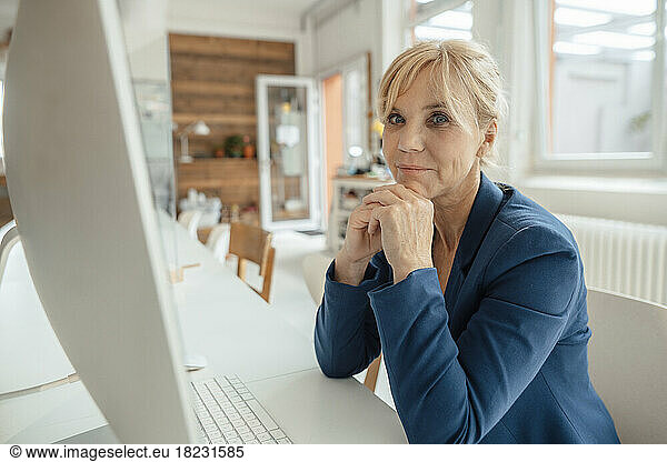 Mature businesswoman in front of desktop PC at office desk
