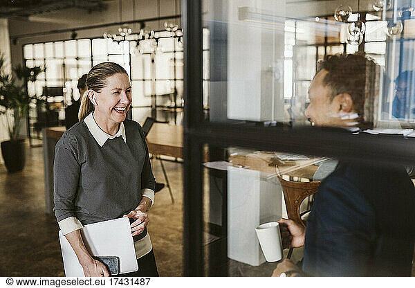 Mature businesswoman laughing with male colleague in office