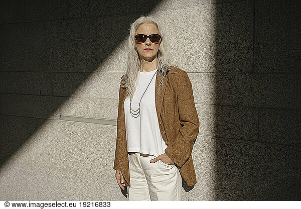 Mature businesswoman standing with hand in pocket