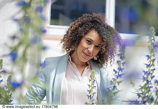 Mature businesswoman with curly hair by flowers