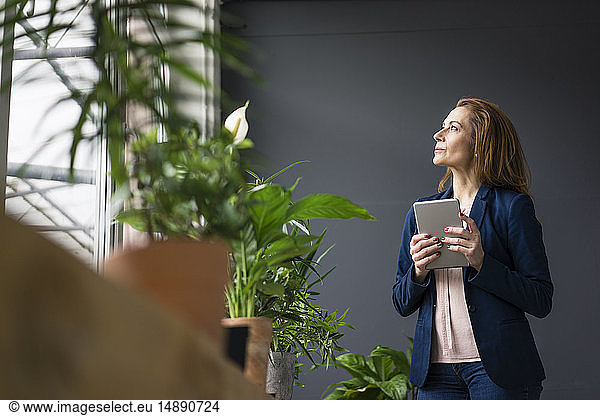 Mature businesswoman working in sustainable office  using digital tablet