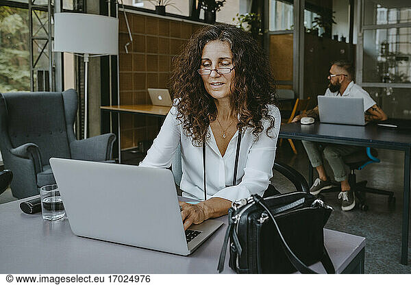 Mature businesswoman working on laptop while sitting in new company