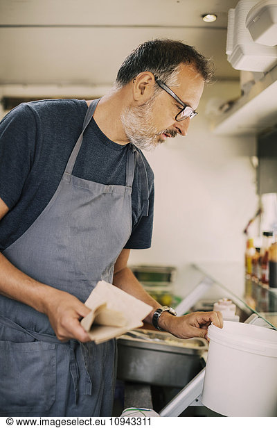 Mature chef working in kitchen of food truck