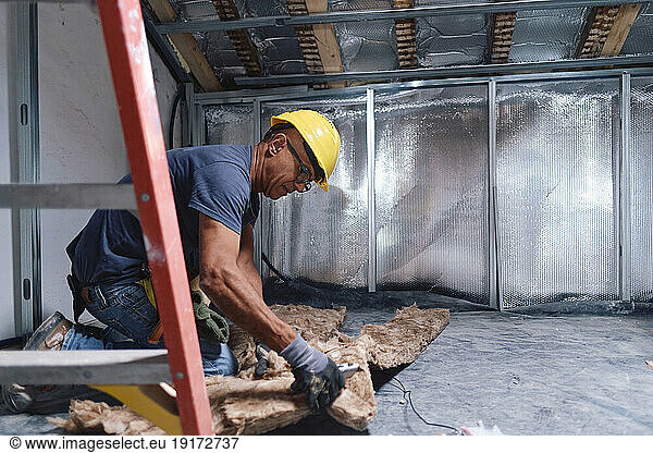 Mature construction worker working on insulation at site