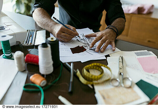 Mature costume designer sketching outfit on paper in studio