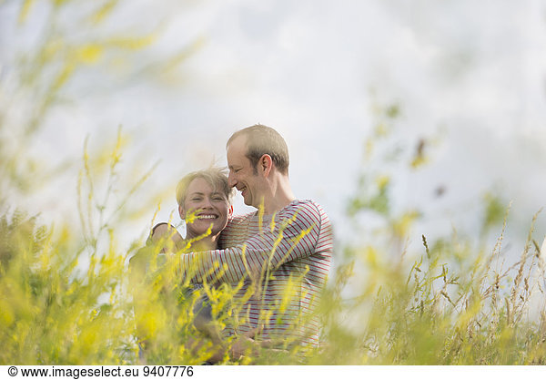 Mature couple embracing each other in field  smiling