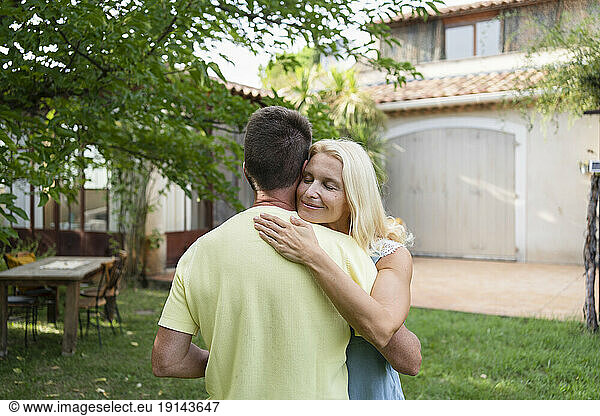 Mature couple embracing in backyard of house