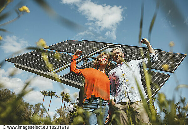 Mature couple flexing muscles standing in front of solar panels