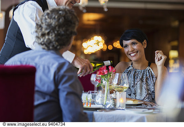 Mature couple in restaurant  waiter pouring white wine