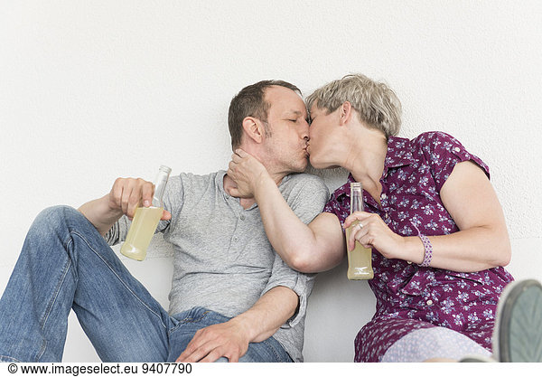 Mature couple kissing each other with drink bottle
