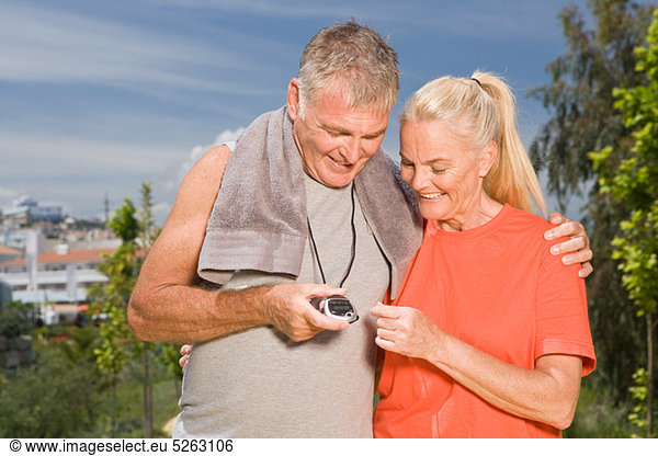 Mature couple looking at stopwatch after workout