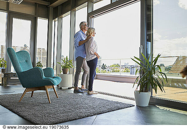 Mature couple looking out of window at home