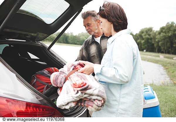 Mature couple removing camping equipment from car boot