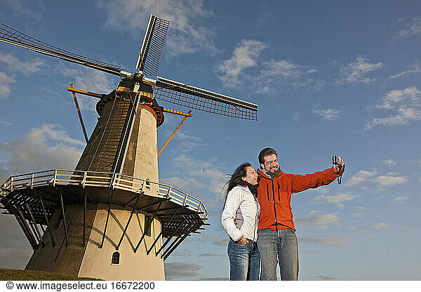 Mature couple taking selfie with windmill in the Netherlands