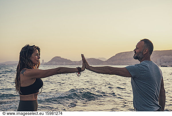 Mature couple touching hands at beach during sunset