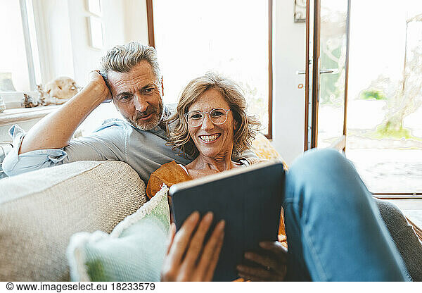 Mature couple using tablet PC sitting on sofa in living room
