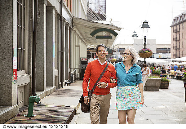 Mature couple walking on sidewalk in city