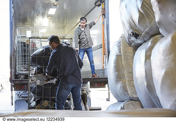 Mature coworkers unloading semi-truck at warehouse