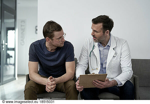 Mature doctor discussing with man at clinic
