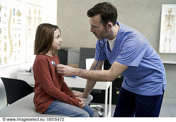 Mature doctor examining girl in clinic