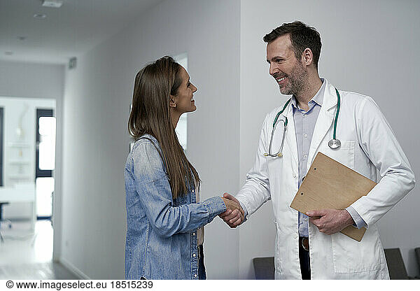 Mature doctor shaking hands with patient at clinic