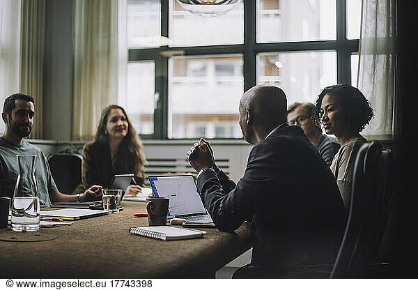 Mature entrepreneur discussing with male and female colleagues in meeting room