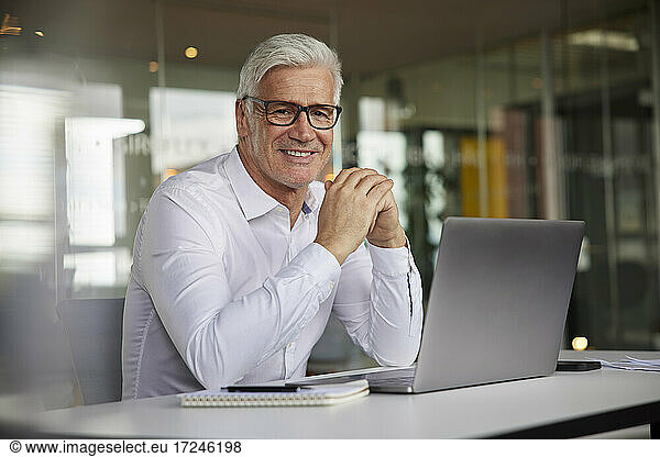 Mature entrepreneur smiling while sitting at desk