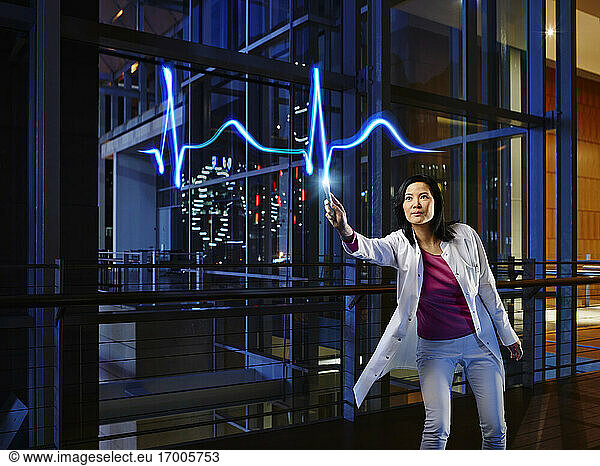 Mature female cardiologist analyzing pulse trace in laboratory at hospital