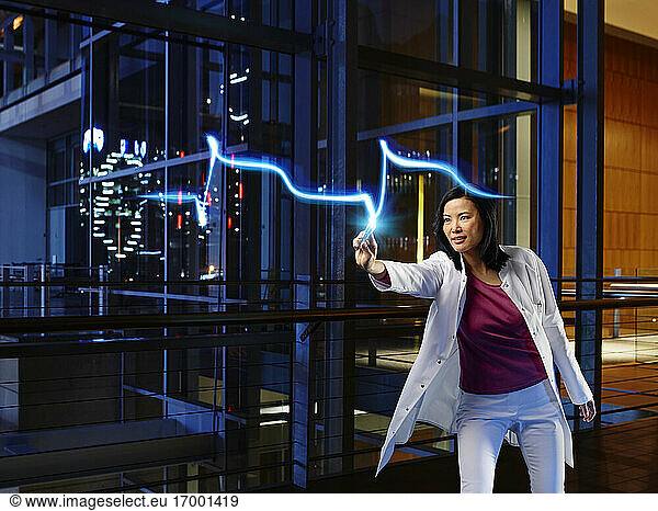 Mature female cardiologist light painting heart attack pulse in laboratory at hospital