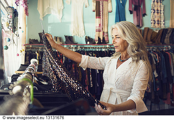 Mature female owner examining dress in clothing store