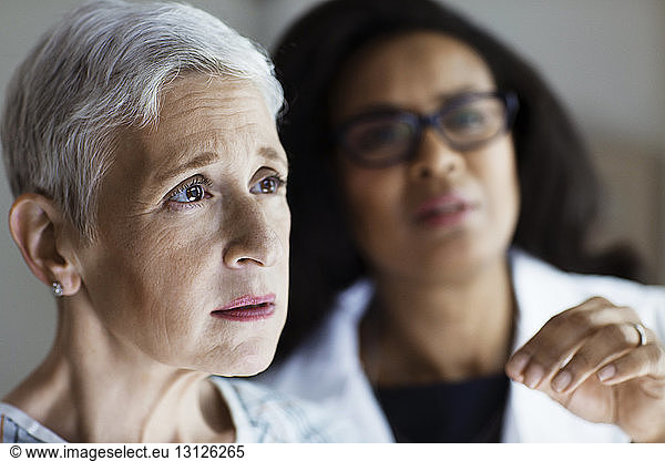 Mature female patient looking away while doctor communicating with her