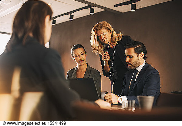 Mature female professional discussing with lawyers at office