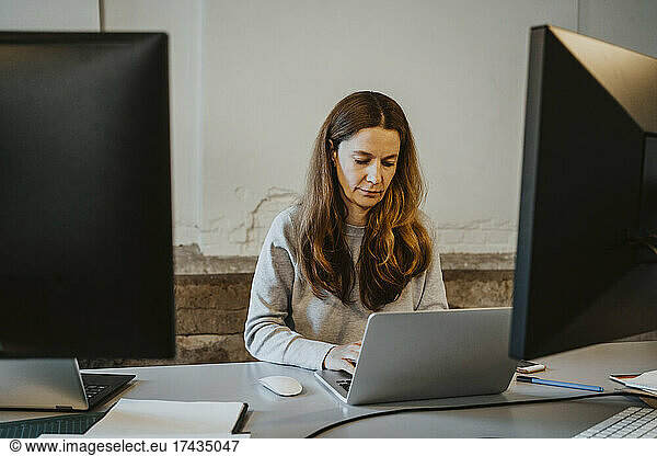 Mature female programmer working on laptop in office