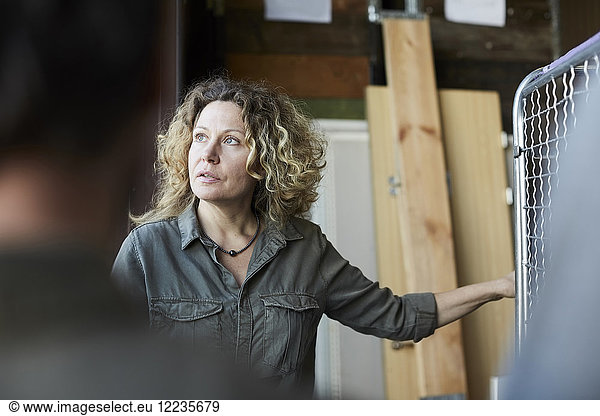 Mature female volunteer with blond curly hair standing in front of coworker at warehouse