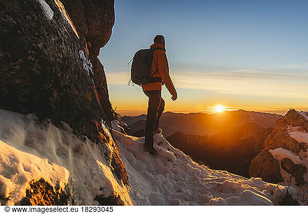 Mature hiker standing in front of mountains at sunset