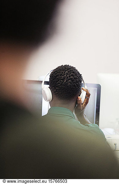 Mature male community college student with headphones at computer