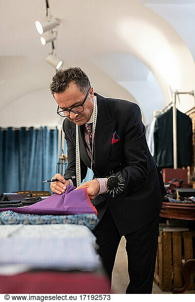 Mature male dressmaker selecting cloth