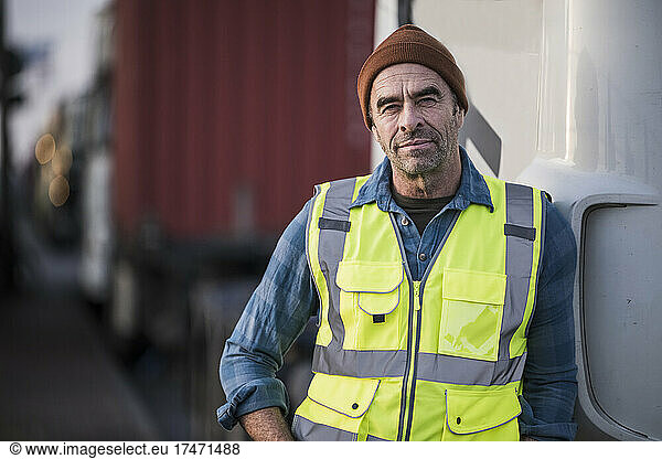 Mature male driver leaning on truck