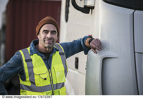Mature male driver standing by truck at dock