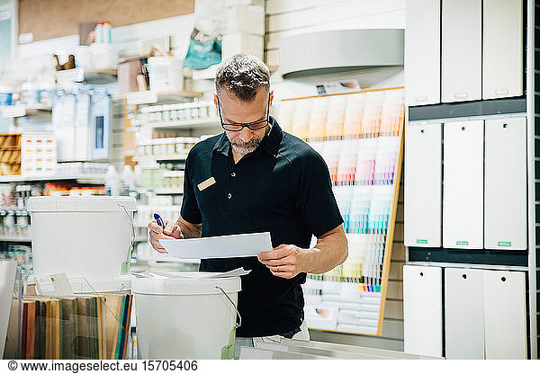 Mature male employee reading document in hardware store
