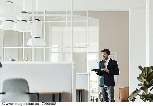 Mature male entrepreneur using digital tablet while standing in office