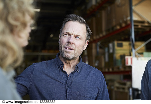Mature male worker looking at female colleague at warehouse