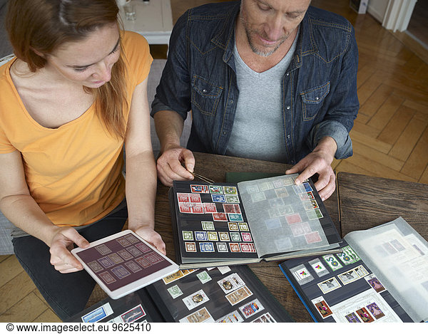 Mature man and young woman looking through stamp collection
